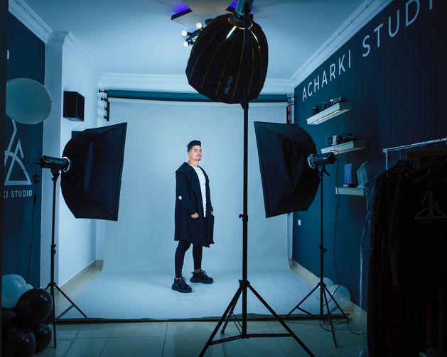 Modelo posando para vender ropa en un estudio con fuentes de iluminación y fondo blanco