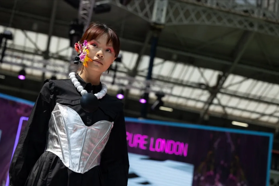 Picture of a woman on the runway that is in a fashion trade show in London.