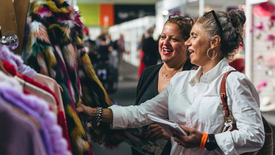 Picture of two women looking for clothes in a trade show.