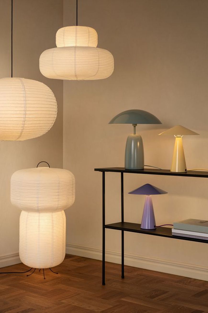Lampade da terra bianche, verdi, gialle e viola nel design d'interni di piccole boutique di abbigliamento