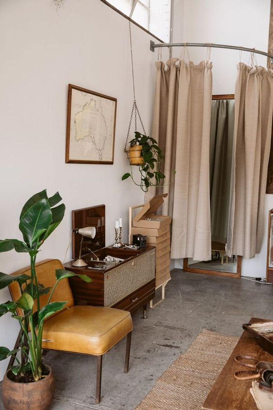 Un angolo all'interno di una piccola boutique di abbigliamento arredato in stile vintage con manufatti antichi