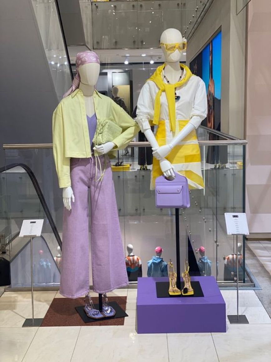 Due manichini che indossano abiti casual in giallo, lilla e bianco all'interno di una piccola boutique di abbigliamento