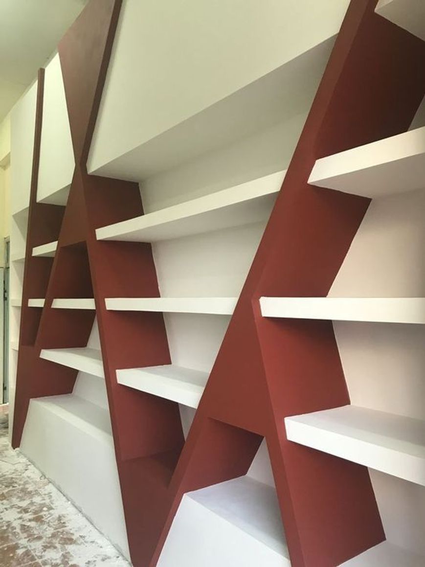 Quattro ripiani diagonali vuoti affiancati in bordeaux e bianco all'interno di una piccola boutique di abbigliamento