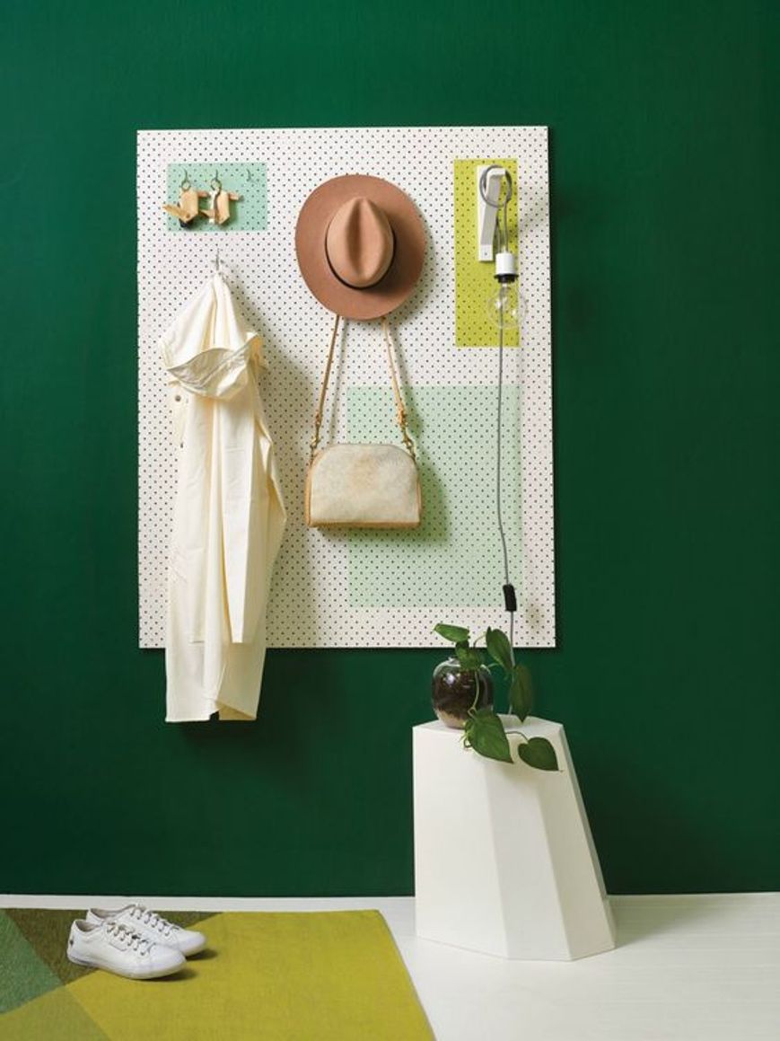 Un'esposizione informale di abiti su una parete verde nel design degli interni di una piccola boutique di abbigliamento