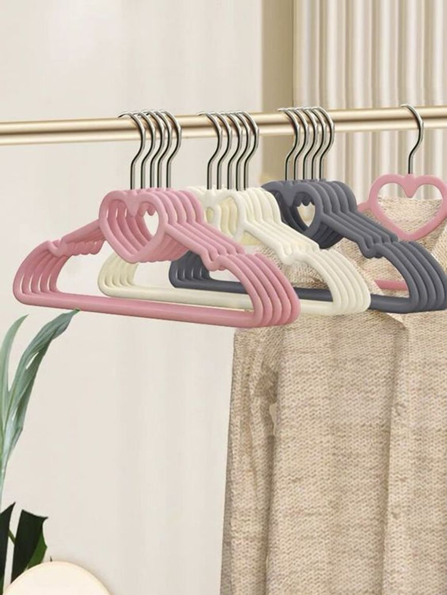 Tredici grucce in velluto di colore rosa, bianco e grigio scuro nell'arredamento di una piccola boutique di abbigliamento