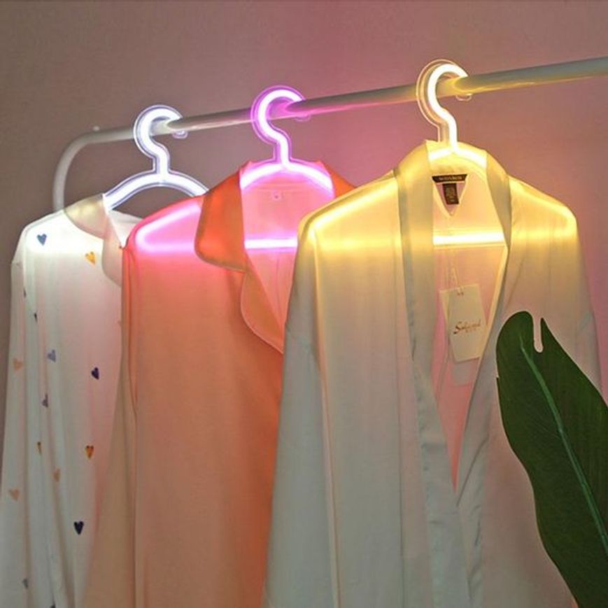 Tre appendini con illuminazione integrata in bianco, rosa e giallo per arredare l'interno di un piccolo negozio di abbigliamento
