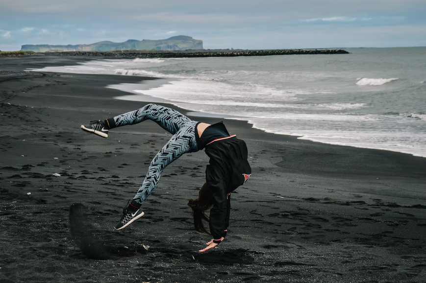 Mujer haciendo yoga en la playa con leggings a rayas blancas y negras