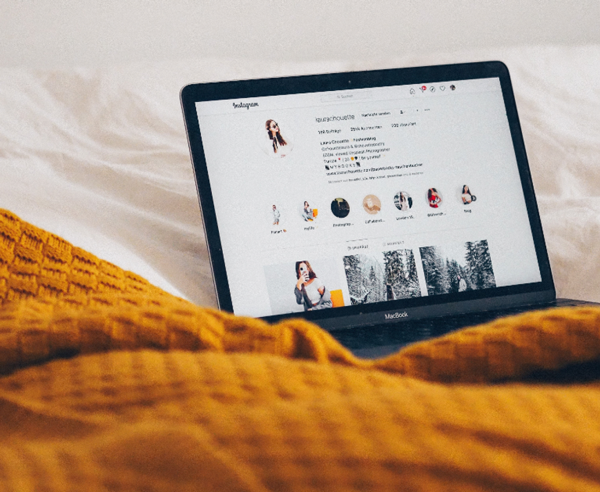 Ein Macbook, das auf einem Bett steht und Instagram geöffnet ist