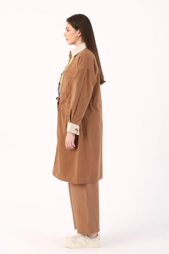 Bir model, Allday toptan giyim markasının 7643 - Modest Trenchcoat - Earth Color toptan Trençkot ürününü sergiliyor.