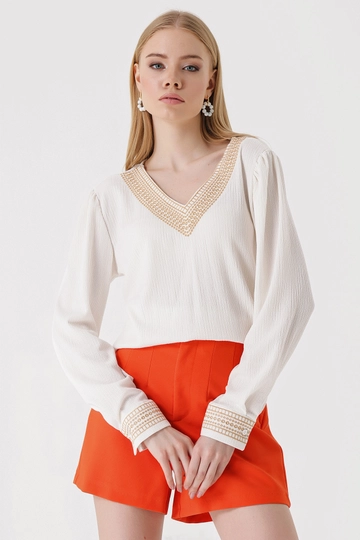 Bir model, Bigdart toptan giyim markasının  Nakışlı V Yaka Örme Bluz - Beyaz
 toptan Bluz ürününü sergiliyor.