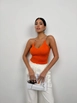 Bir model,  toptan giyim markasının bla11505-stone-strap-knitted-blouse-orange toptan  ürününü sergiliyor.