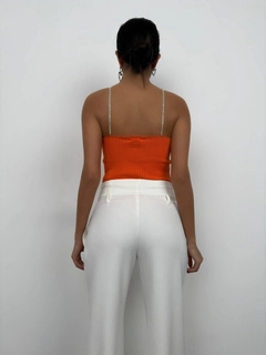 Bir model, Black Fashion toptan giyim markasının bla11505-stone-strap-knitted-blouse-orange toptan Crop Top ürününü sergiliyor.