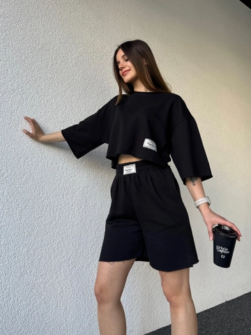 Bir model, CAPPITONE toptan giyim markasının  Etiketli Şortlu Takim Siyah
 toptan Takım ürününü sergiliyor.