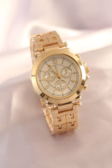 Bir model, Ebijuteri toptan giyim markasının  Gold Renk Metal Kordon Beyaz İç Tasarım Kadın Saat
 toptan Saat ürününü sergiliyor.