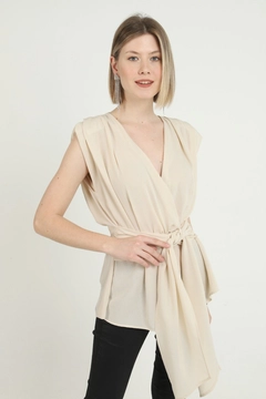 Bir model, Elisa toptan giyim markasının ELS10096 - Belted Zero Sleeve Waistband Blouse - Beige toptan Bluz ürününü sergiliyor.