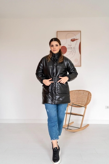Bir model, Elisa toptan giyim markasının  Kemerli Deri Şişme Mont - Siyah
 toptan Kaban ürününü sergiliyor.