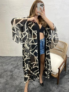 Bir model, Fame toptan giyim markasının FME10665 - Kimono - Black Beige toptan Kimono ürününü sergiliyor.