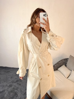 Bir model, Fame toptan giyim markasının 29693 - Trenchcoat - Cream toptan Trençkot ürününü sergiliyor.