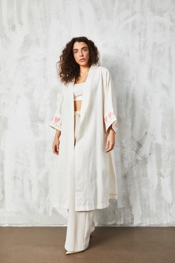 Bir model, First Angels toptan giyim markasının  Pembe Nakışlı Uzun Kimono
 toptan Kimono ürününü sergiliyor.