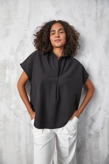 Bir model, First Angels toptan giyim markasının  Siyah Kısa Kollu Poplin Oversize Gömlek
 toptan  ürününü sergiliyor.