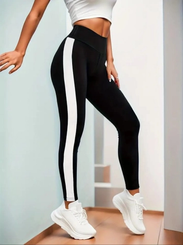 Bir model, Janes toptan giyim markasının  Kadın Yanları Beyaz Şerit Dalgıç Tayt - Siyah
 toptan Tayt ürününü sergiliyor.
