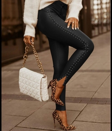Bir model, Janes toptan giyim markasının  Kadın Beli Kuşaklı Yırtmaç Detay Boncuk Şeritli Deri Tayt - Siyah
 toptan Tayt ürününü sergiliyor.