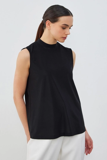 Bir model, Kadriye Baştürk toptan giyim markasının  Teva İpek Örme Kolsuz İç Giyim Bluz Siyah
 toptan Bluz ürününü sergiliyor.