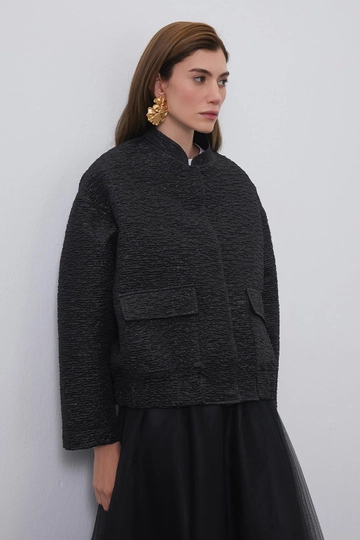 Bir model, Kadriye Baştürk toptan giyim markasının  Niola Tafta Jakarlı Ceket Siyah
 toptan Ceket ürününü sergiliyor.