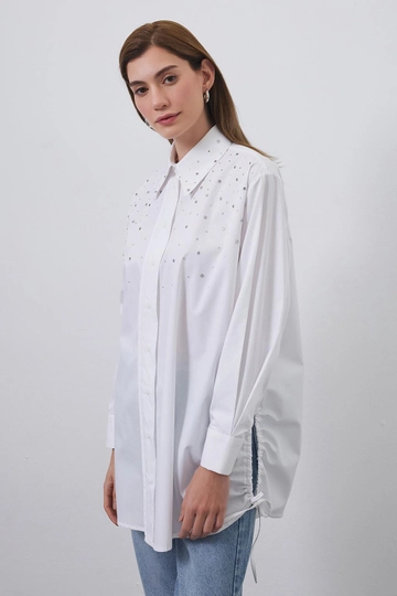 Bir model, Kadriye Baştürk toptan giyim markasının  Anita Taşlı Büzgülü Gömlek Ekru
 toptan Gömlek ürününü sergiliyor.