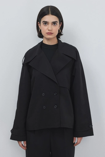 Bir model, Kadriye Baştürk toptan giyim markasının  Çift Düğmeli Trençkot - Siyah
 toptan Trençkot ürününü sergiliyor.