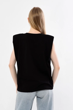 Bir model, Kuxo toptan giyim markasının 44212 - KUXO New York Printed Shoulder Pad Zero Sleeve T-Shirt toptan Tişört ürününü sergiliyor.