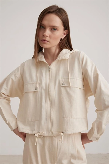 Bir model, Levure toptan giyim markasının  Kapüşon Detaylı Kadın Keten Ceket - Krem
 toptan Hoodie ürününü sergiliyor.