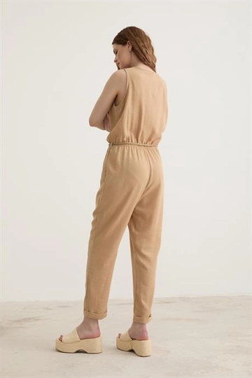 Bir model, Levure toptan giyim markasının  Kemer Detaylı Uzun Keten Tulum Bisküvi
 toptan Tulum ürününü sergiliyor.