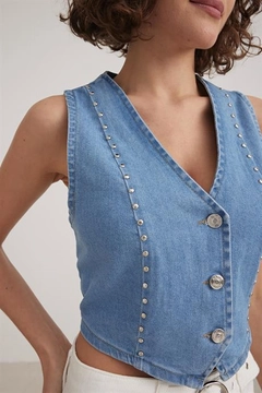 Bir model, Levure toptan giyim markasının lev10328-staple-detailed-denim-vest-blue toptan Yelek ürününü sergiliyor.