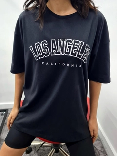 Bir model, MyBee toptan giyim markasının MYB10180 - T-Shirt Los Angeles - Black toptan Tişört ürününü sergiliyor.