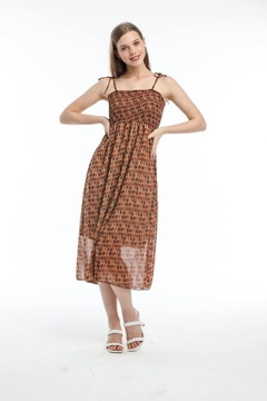 Bir model, MyBee toptan giyim markasının MYB10135 - Strap Dress - Brown toptan Elbise ürününü sergiliyor.