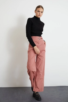 Bir model, Newgirl toptan giyim markasının new10009-gabardine-fabric-buckle-belt-wide-leg-women's-trousers-dusty-rose toptan Pantolon ürününü sergiliyor.
