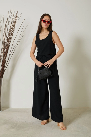 Bir model, Newgirl toptan giyim markasının  Asimetrik Sırt Detay Atlet Yaka Bel Lastik Pantolon Kadın Yazlık Takım - Siyah
 toptan Takım ürününü sergiliyor.