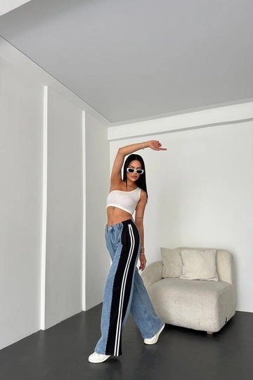 Bir model, Newgirl toptan giyim markasının  Şerit Detaylı Bol Kesim Denim Pantolon - Mavi
 toptan Pantolon ürününü sergiliyor.