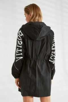 Bir model, Robin toptan giyim markasının 21322 - Trenchcoat - Black toptan Trençkot ürününü sergiliyor.