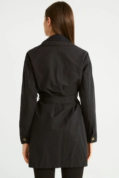Bir model, Robin toptan giyim markasının 32090 - Trenchcoat - Black toptan Trençkot ürününü sergiliyor.