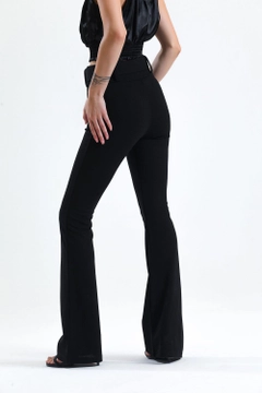 Una modelo de ropa al por mayor lleva sns10869-black-flared-belted-knitted-fabric-trousers-pnt32439, Pantalón turco al por mayor de SENSE