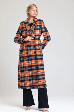 Bir model, SENSE toptan giyim markasının sns10877-plaid-lined-cashmere-long-coat-orange-&-black toptan Kaban ürününü sergiliyor.