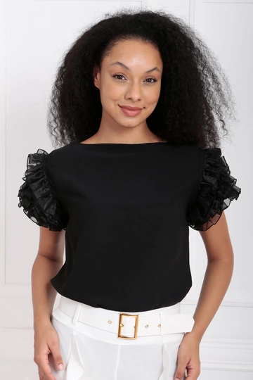 Bir model, SENSE toptan giyim markasının  Sense Siyah Organze Fırfırlı Ermuarlı Cesika Bluz
 toptan Bluz ürününü sergiliyor.
