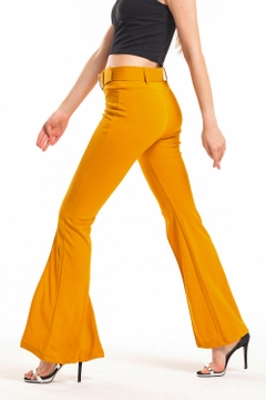 Bir model, SENSE toptan giyim markasının sns10078-mustard-belted-pique-steel-trousers-with-flared-legs toptan Pantolon ürününü sergiliyor.