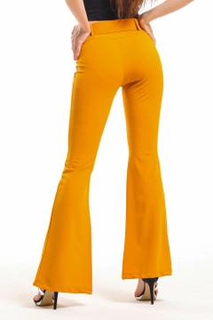 Bir model, SENSE toptan giyim markasının sns10078-mustard-belted-pique-steel-trousers-with-flared-legs toptan Pantolon ürününü sergiliyor.