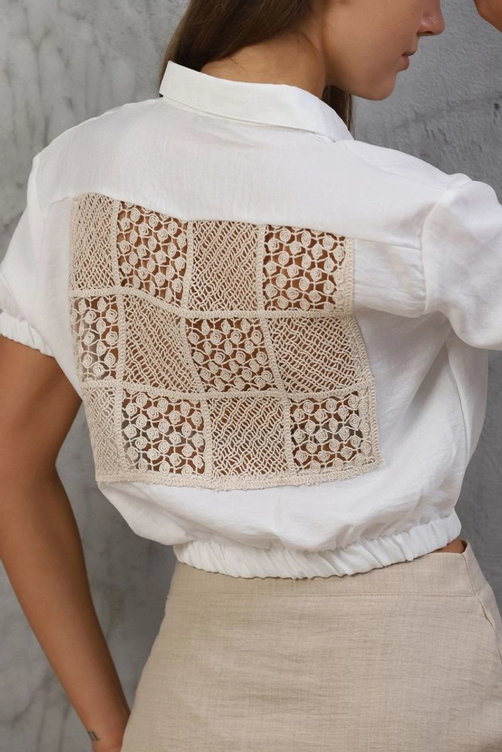 Bir model, Topshow toptan giyim markasının top10320-shirt-with-laced-back-cream toptan Crop Top ürününü sergiliyor.