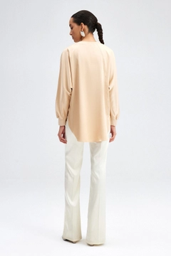 Bir model, Touche Prive toptan giyim markasının tou12236-satin-pocket-detail-tunic-beige toptan Tunik ürününü sergiliyor.