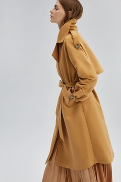Bir model, Touche Prive toptan giyim markasının 33917 - Double Breasted Trenchcoat toptan Trençkot ürününü sergiliyor.