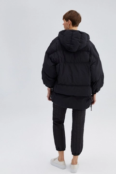 Bir model, Touche Prive toptan giyim markasının 33933 - Hooded Oversize Puffer Jacket toptan Kaban ürününü sergiliyor.
